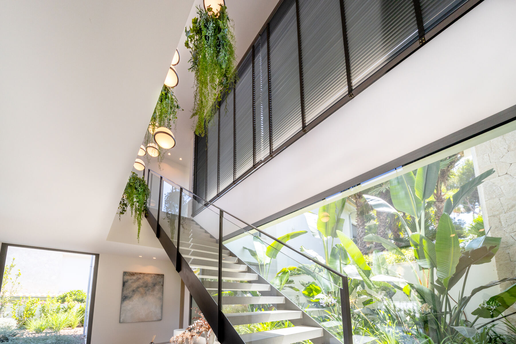 Double-height stairwell with glass balustrade and hanging planting