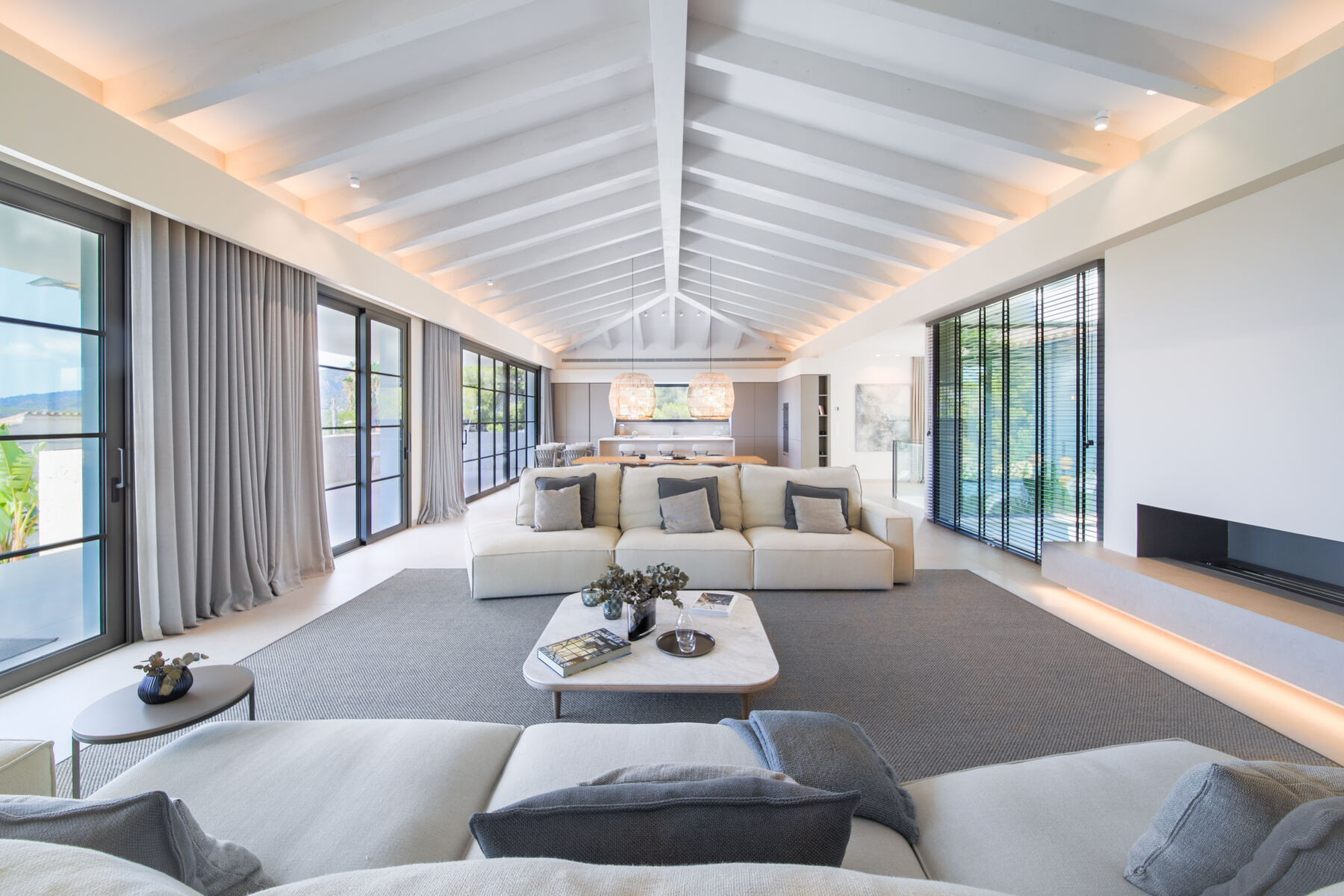 Open-plan living room with exposed white beams and full-height glazing in a Mallorca villa